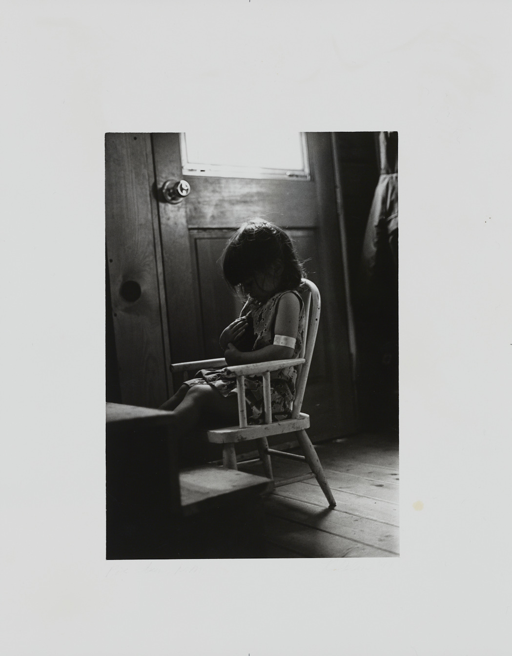 Young girl sitting in a child's rocking chair, cradling a small animal