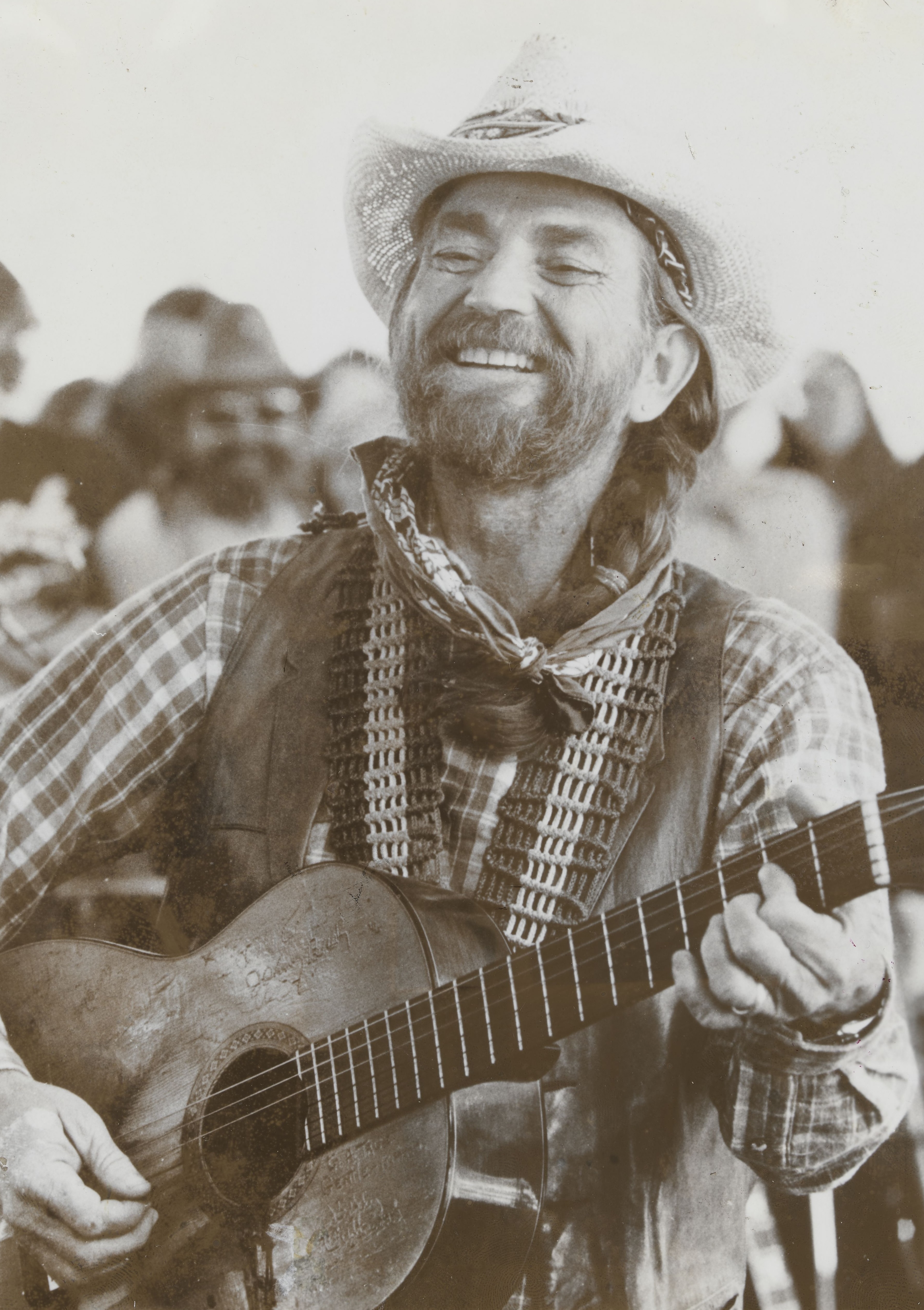 Willie Nelson smiling and playing his guitar Trigger