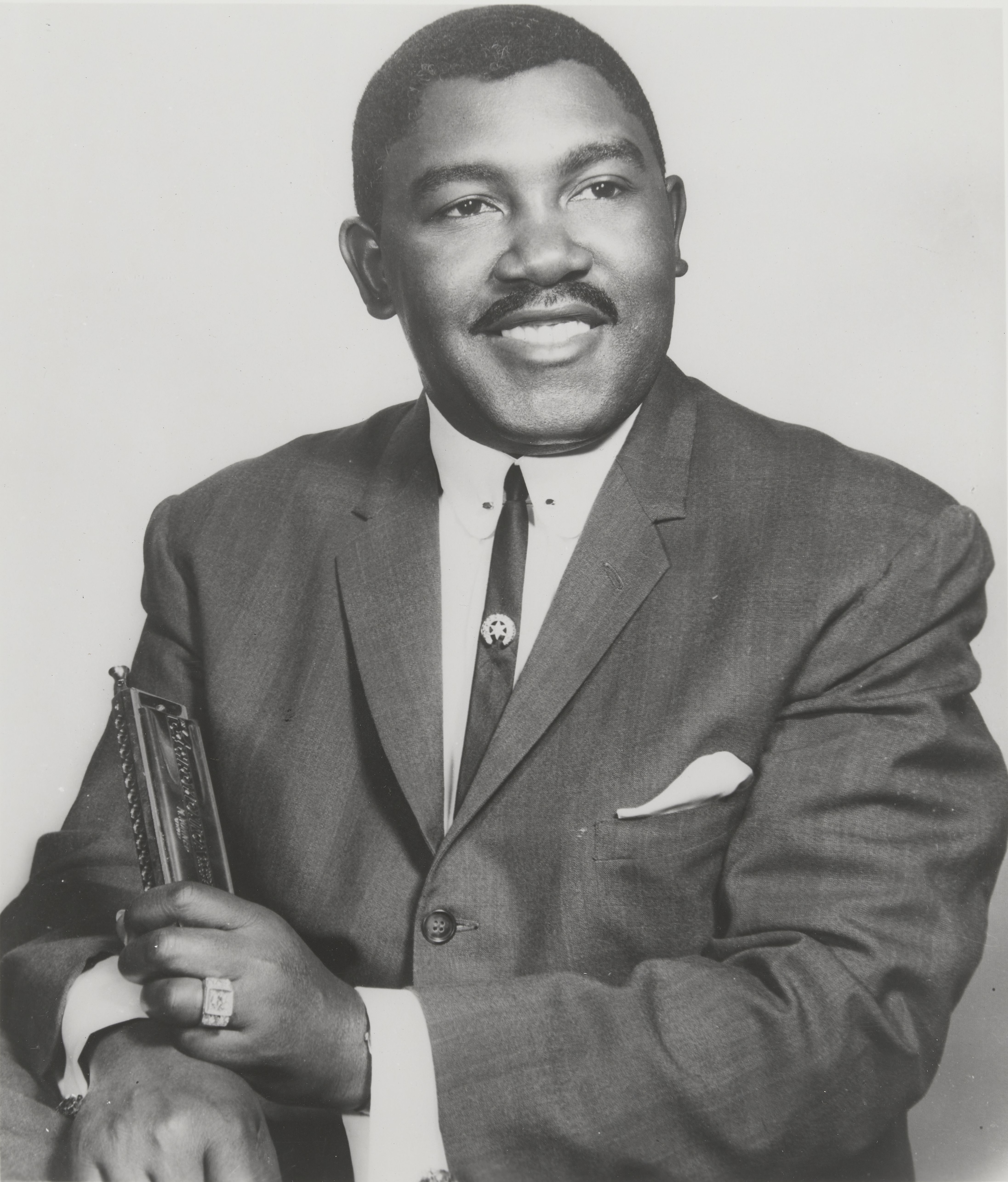 Headshot of blues musician Junior Parker holding a harmonica.